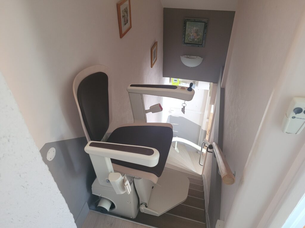 Vue plongeante sur monte-escalier installé dans escalier droit avec double rampe