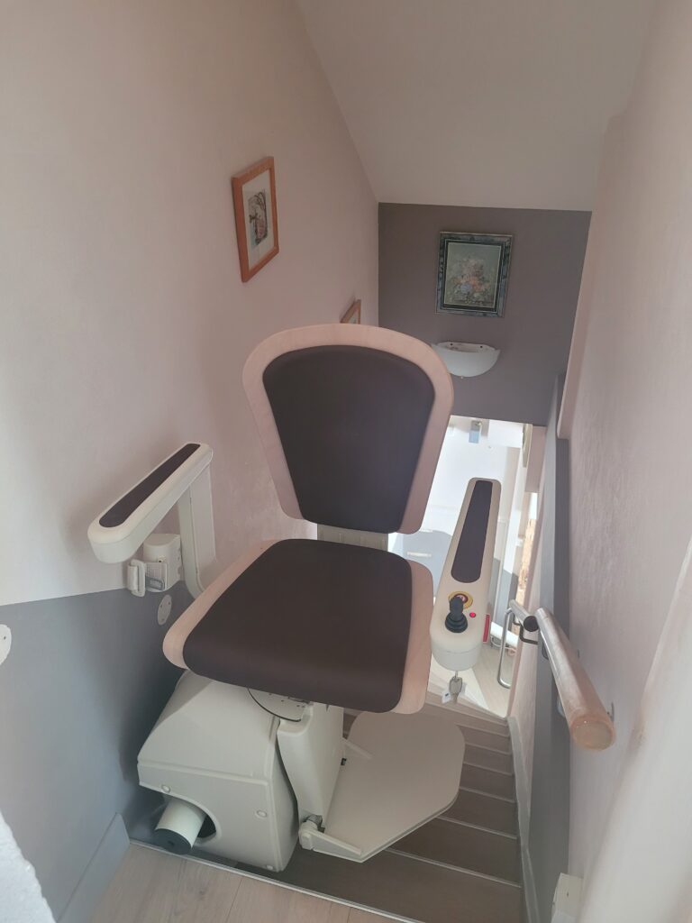 Vue plongeante sur monte-escalier installé dans escalier droit avec double rampe