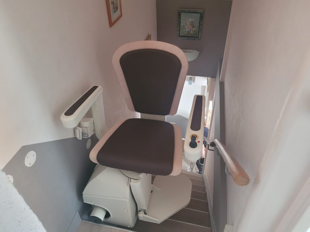 Vue plongeante sur monte-escalier installé dans escalier droit avec double rampe