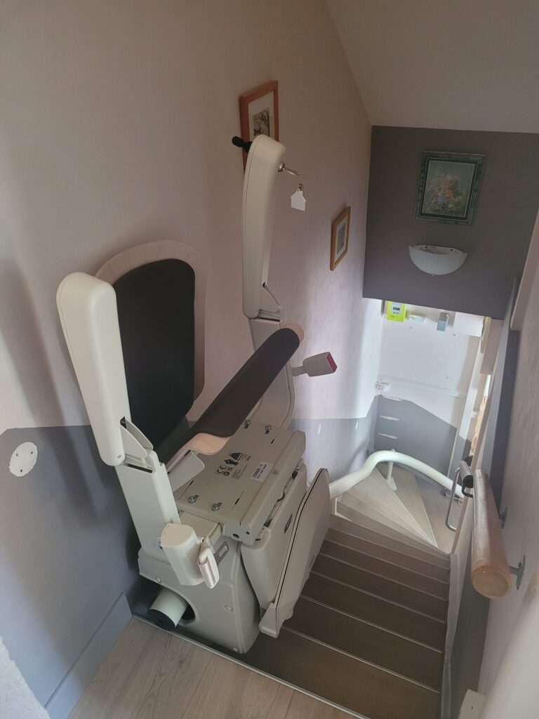 Vue plongeante sur monte-escalier installé dans escalier droit avec double rampe