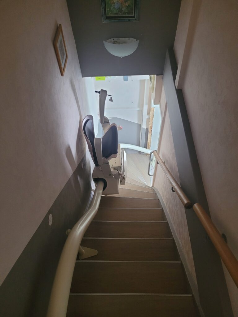 Vue plongeante sur monte-escalier installé dans escalier droit avec double rampe
