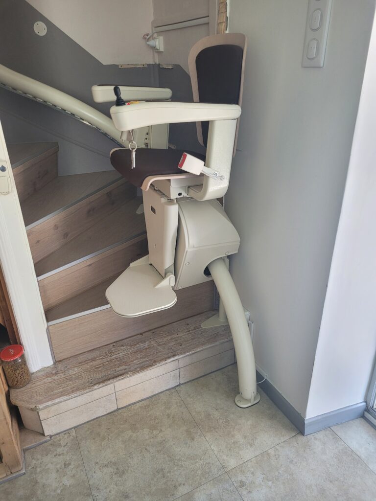 Vue plongeante sur monte-escalier installé dans escalier droit avec double rampe