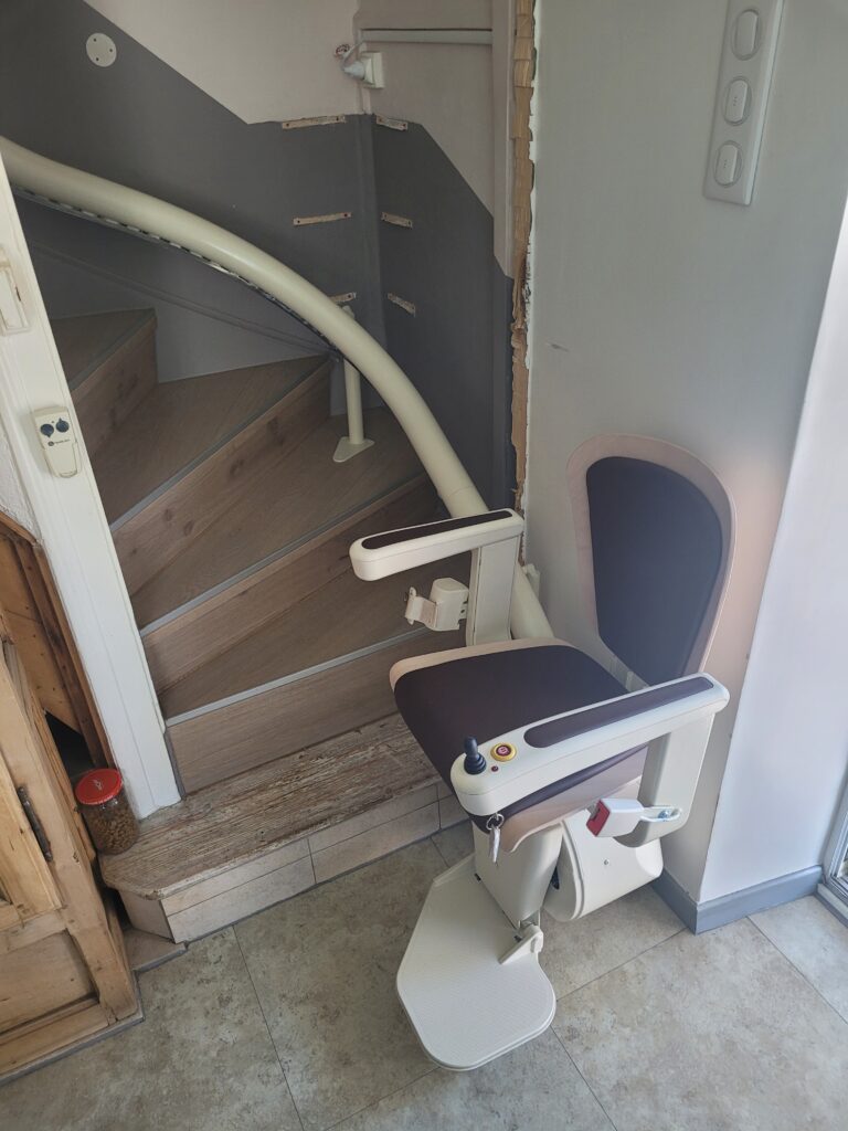 Vue plongeante sur monte-escalier installé dans escalier droit avec double rampe