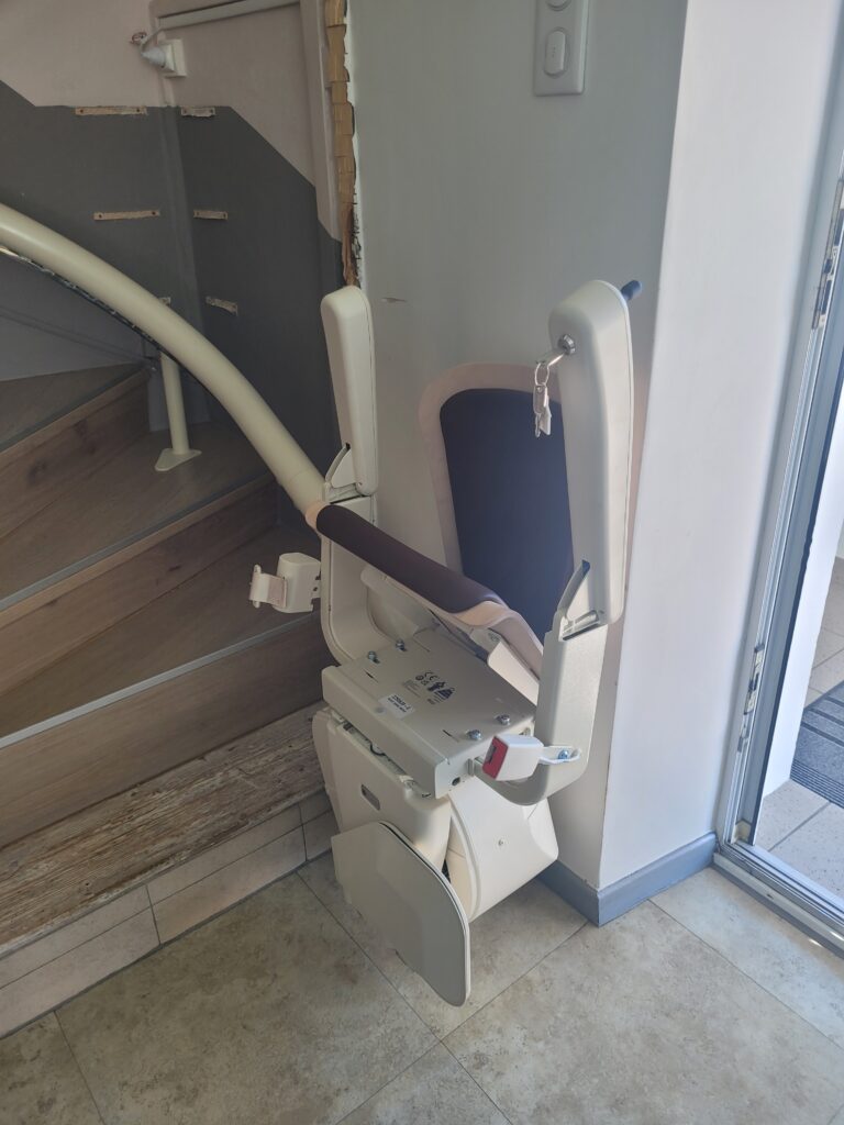 Vue plongeante sur monte-escalier installé dans escalier droit avec double rampe