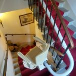 Monte-escalier avec siège beige installé sur escalier courbe avec moquette rouge