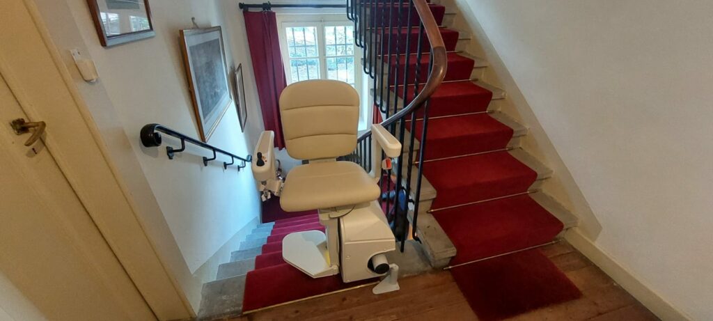 Monte-escalier avec siège beige installé sur escalier courbe avec moquette rouge