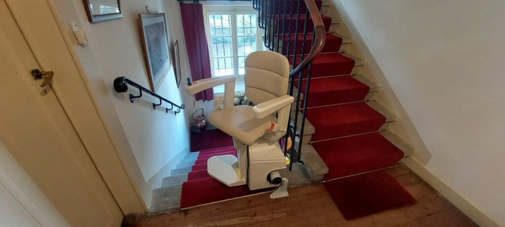 Monte-escalier avec siège beige installé sur escalier courbe avec moquette rouge